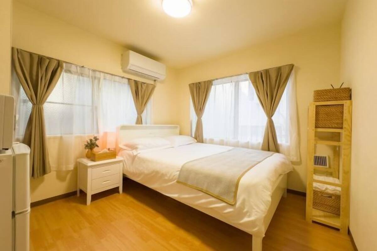 A bedroom with a bed, bedside table, lamp, and a small shelf.