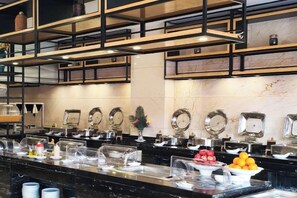 A buffet area with multiple serving stations, clear glass covers, and a variety of food items. - Hotel Anda (Malabo)
