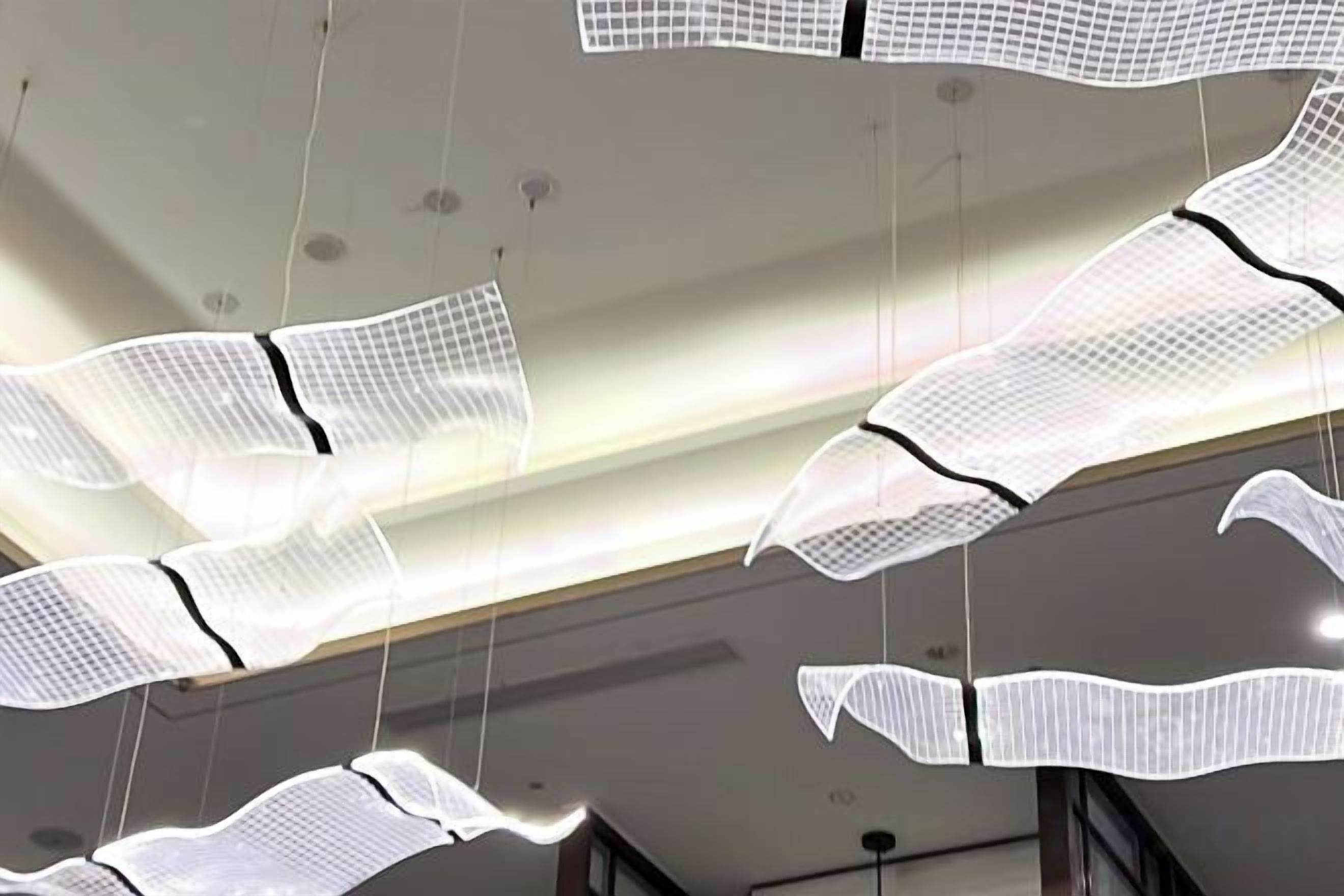 A ceiling with hanging, translucent, grid-like structures.