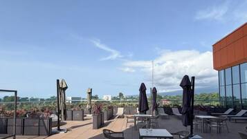 Terraço no telhado com área de estar ao ar livre, vista da cidade e estrutura de prédio moderna.