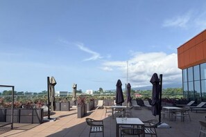 A rooftop terrace with outdoor seating, a view of the city, and a modern building structure. - Hotel Anda (Malabo)