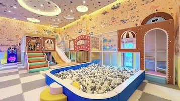 Een binnenspeelruimte met glijbanen, een ballenbak en klimconstructies.
