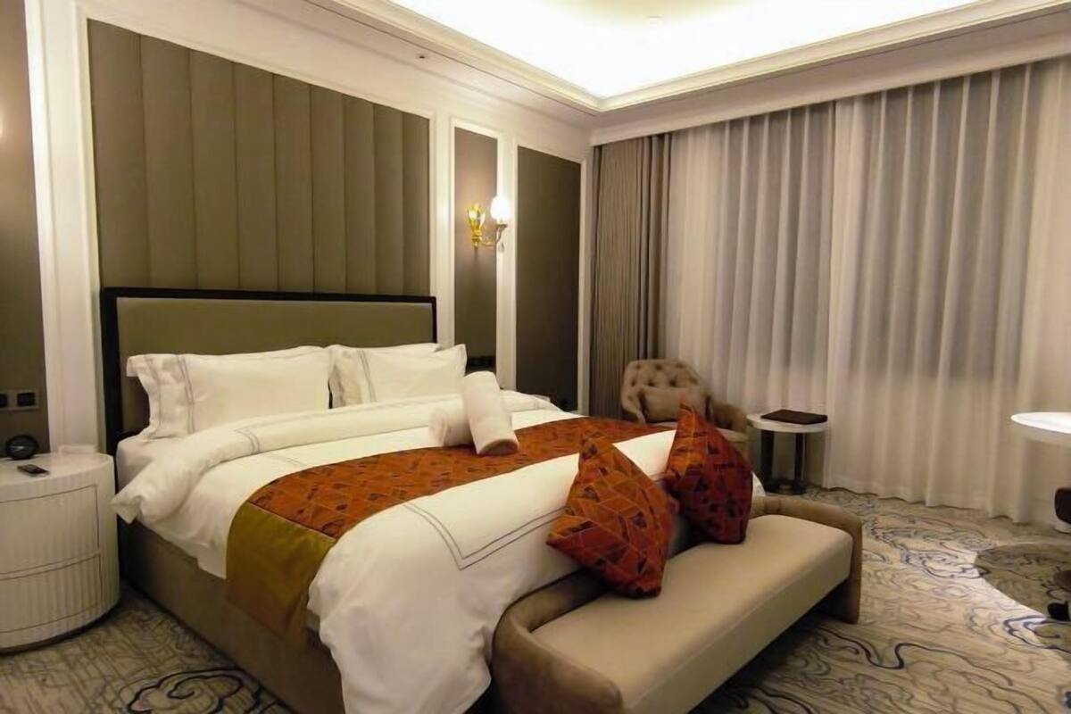 Une chambre d’hôtel avec un grand lit, un canapé, une petite table et une lampe.
