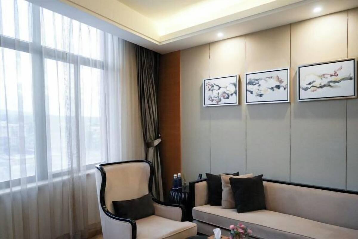 Une chambre d’hôtel avec un canapé, un fauteuil et trois œuvres d’art encadrées accrochées au mur.
