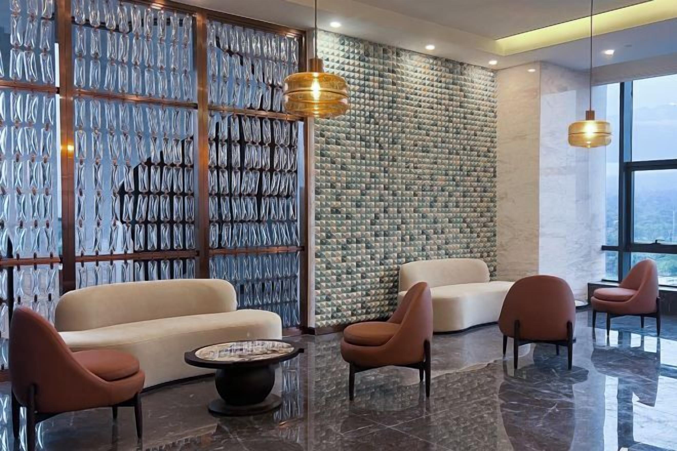 A modern lobby with a seating area, a patterned wall, and a large window.
