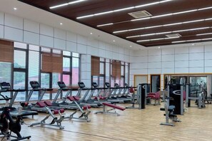 A gym with treadmills, weight machines, and a large windowed wall. - Hotel Anda (Malabo)