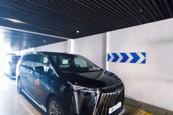 A black SUV parked in a parking garage with directional arrows on the wall. - Hotel Anda (Malabo)