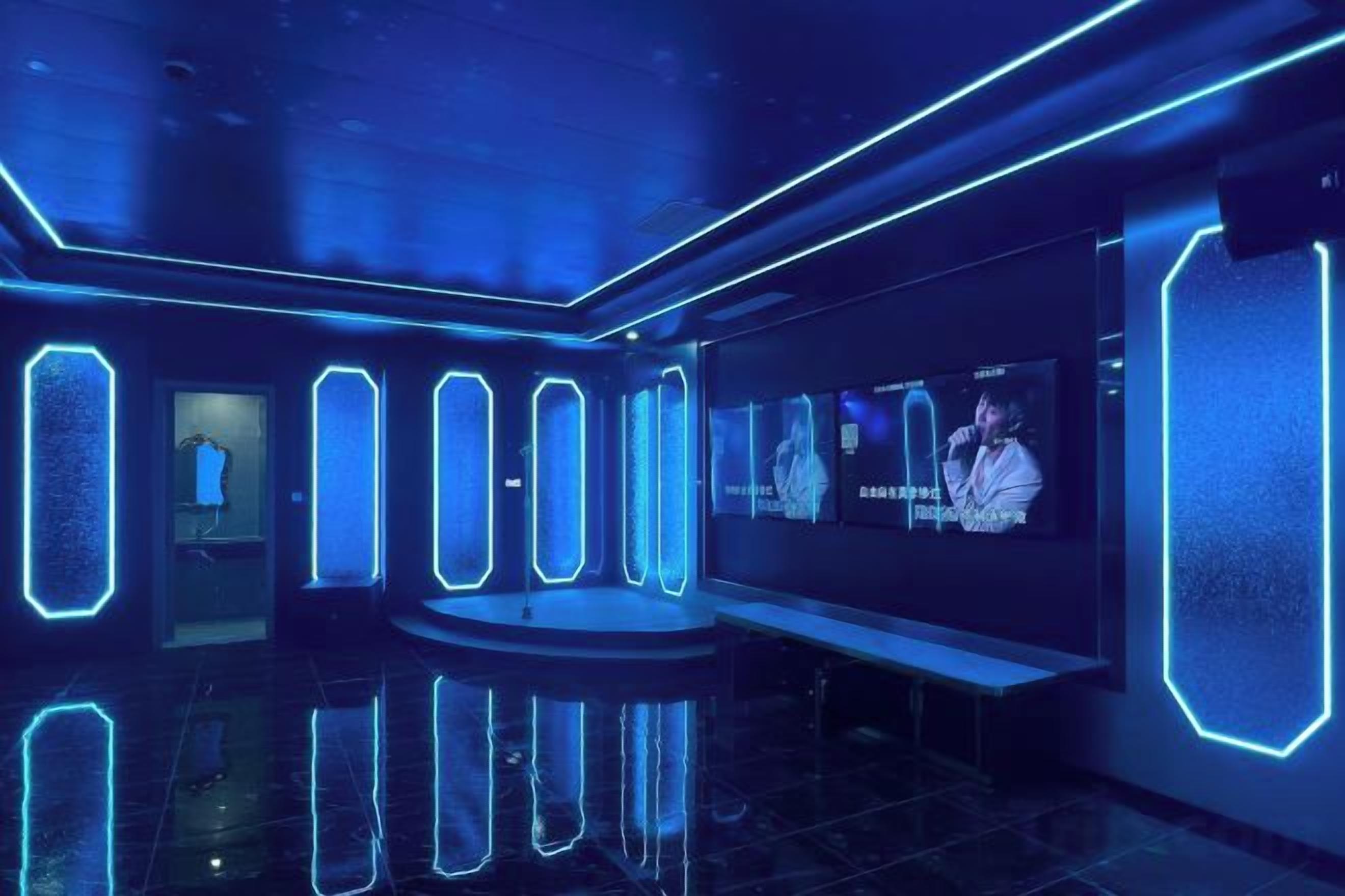 A modern interior with a reflective floor, a seating area, and a large screen displaying an image.