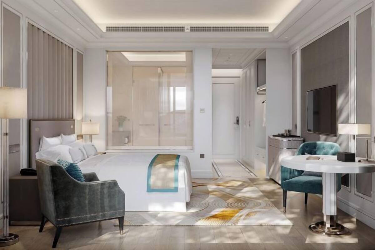 Une chambre d’hôtel équipée d’un lit, d’un bureau, d’une chaise, d’une télévision et d’une grande fenêtre.