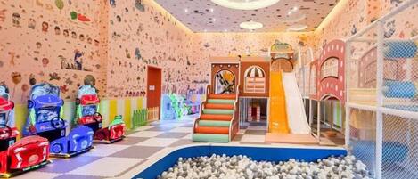 A children's play area with a ball pit, climbing structures, and colorful ride-on toys.