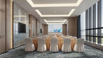 A conference room with a long table, chairs, and a large screen.