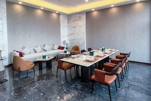 Una sala de conferencias con una larga mesa, sillas, un sofá y una lámpara.