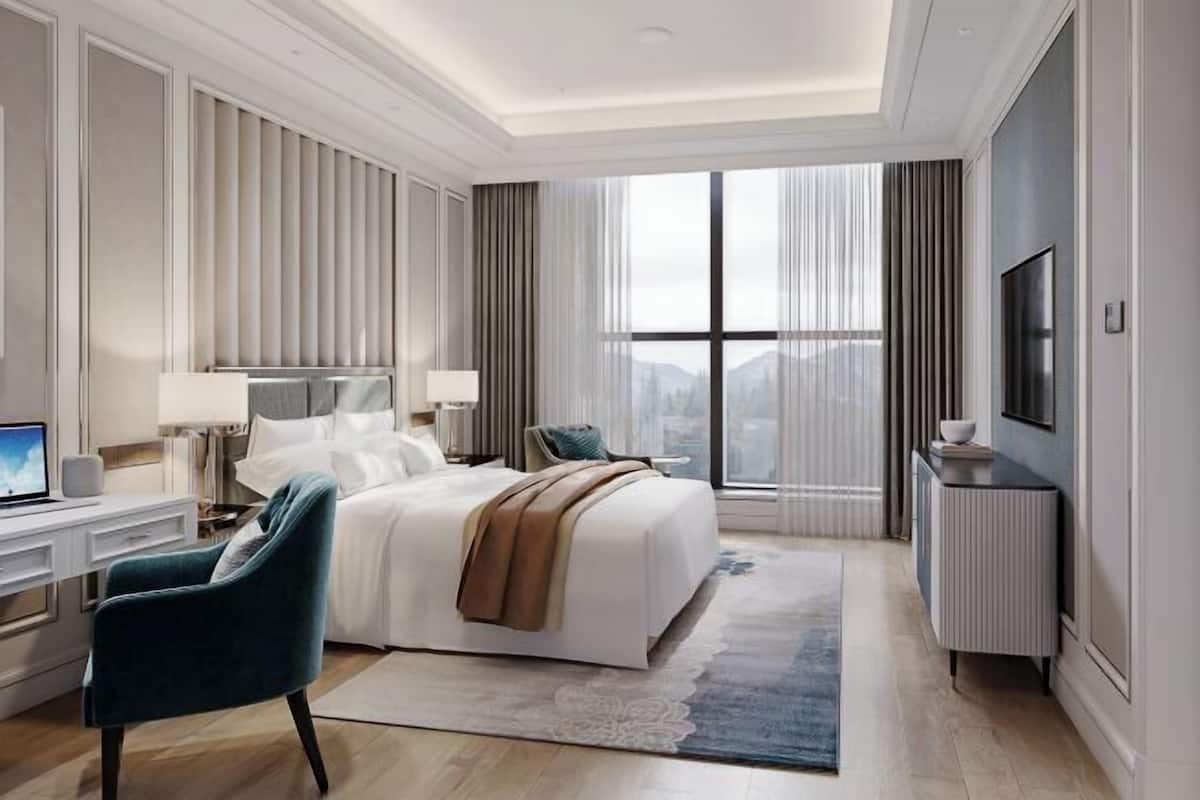 Une chambre d’hôtel moderne dotée d’un grand lit, d’un bureau avec un ordinateur, d’une télévision et offrant une vue sur la ville grâce à de grandes fenêtres.