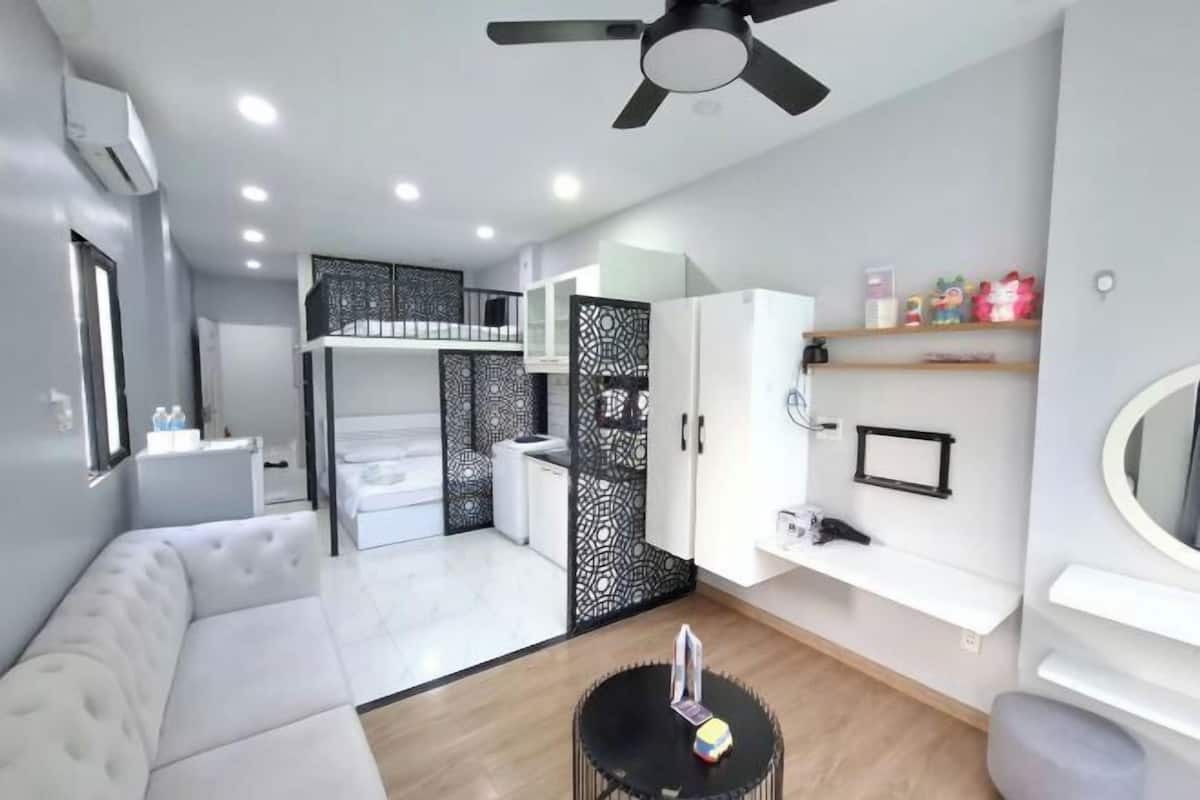 A modern room with a white sofa, a black round table, a ceiling fan, a white cabinet, and a decorative black partition.