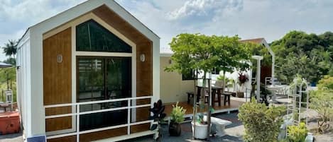 A modern building with a large window, surrounded by potted plants and a gravel area.