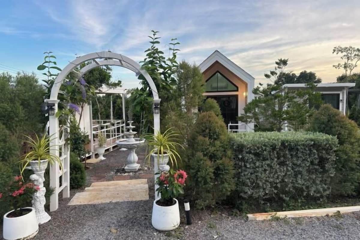Ein modernes Haus mit Garteneingang, einem weißen Bogen und einem Weg zum Haus.