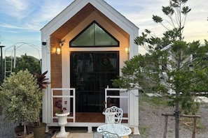 Una pequeña estructura de madera blanca con techo inclinado y puerta de cristal.