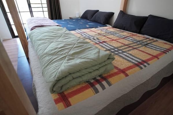 Una cama con una manta escocesa, una manta azul y una manta verde.