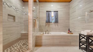 A modern bathroom with a shower, a bathtub, and a vanity with a bottle and towels. - Indoor Pool, Theater, Hot Tub & Mountain Views Near Dollywood Crimson Crest by Avantstay (Sevierville)