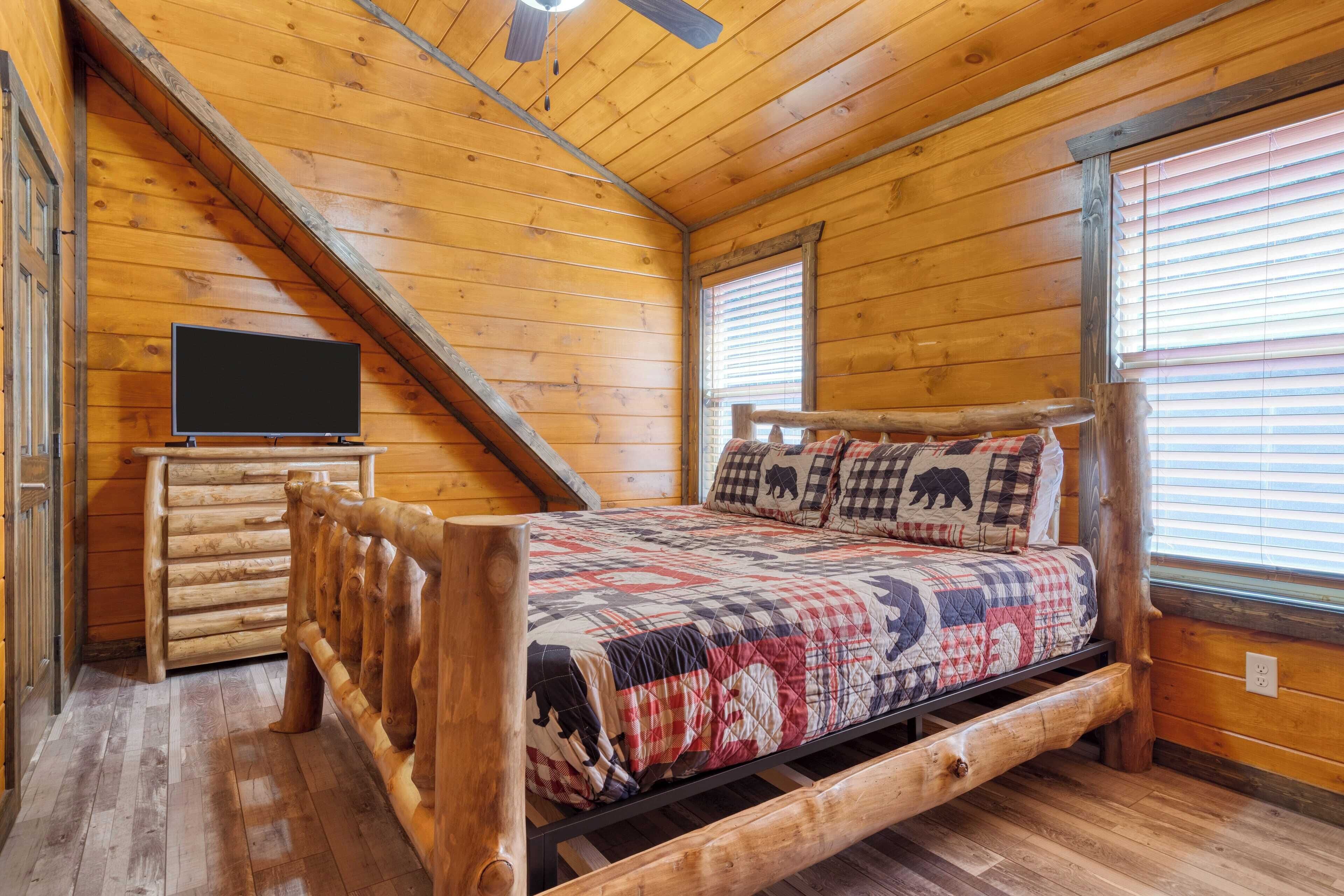 Un dormitorio de cabaña de madera con una cama, un aparador de madera y un ventilador de techo.
