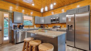 Une cuisine moderne dotée d’appareils électroménagers en acier inoxydable, de plans de travail en granit et d’éléments décoratifs en bois.