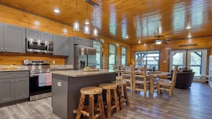 A modern kitchen with granite countertops, stainless steel appliances, and a central island with stools. - Indoor Pool, Theater, Hot Tub & Mountain Views Near Dollywood Crimson Crest by Avantstay (Sevierville)