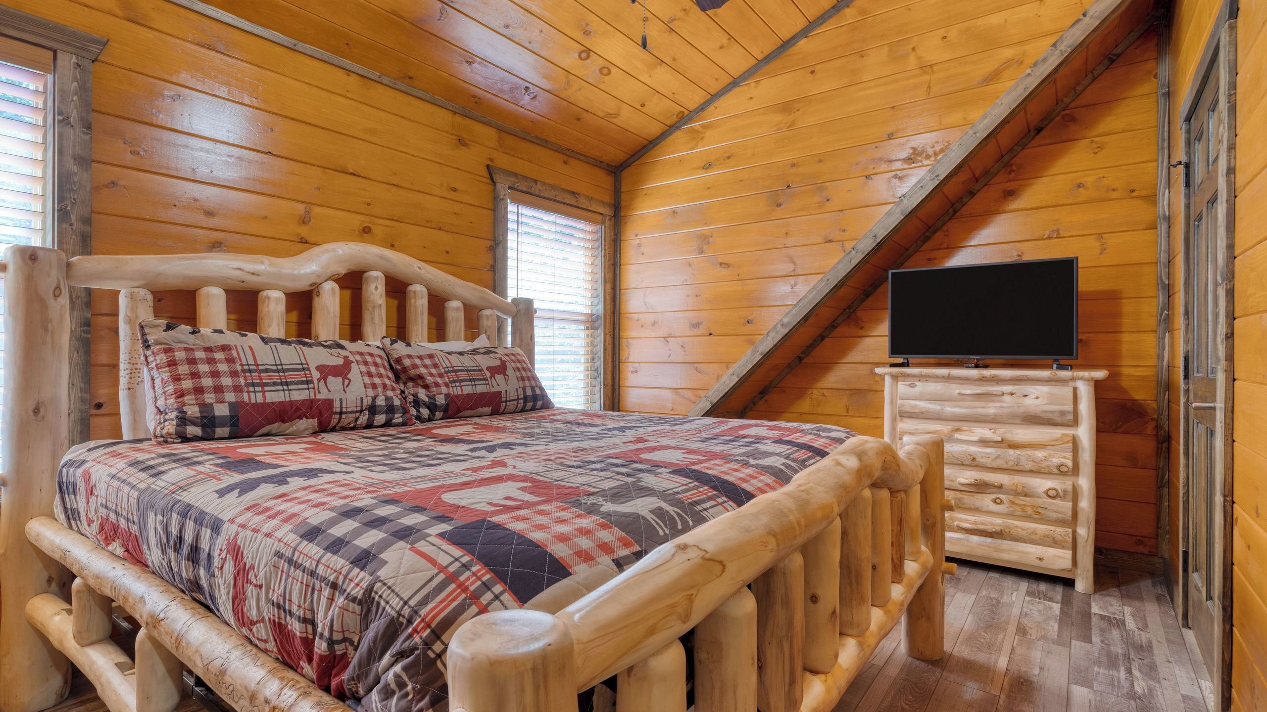 Une chambre dans une cabane en bois, avec un lit, une commode et un téléviseur.