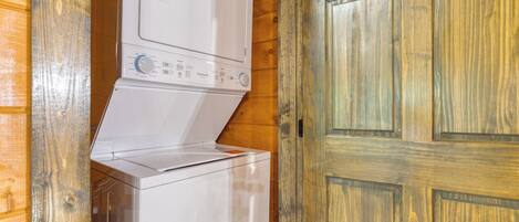 Eine Waschmaschine mit Frontlader in einer Holzhütte mit einer Holztür.