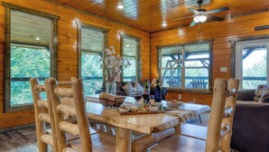 L’intérieur d’une cabane en bois, avec une table à manger, des chaises et un ventilateur de plafond.