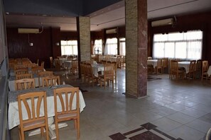 A spacious dining area with multiple tables and chairs, large pillars, and a tiled floor. - New Geisum Resort (Hurghada)