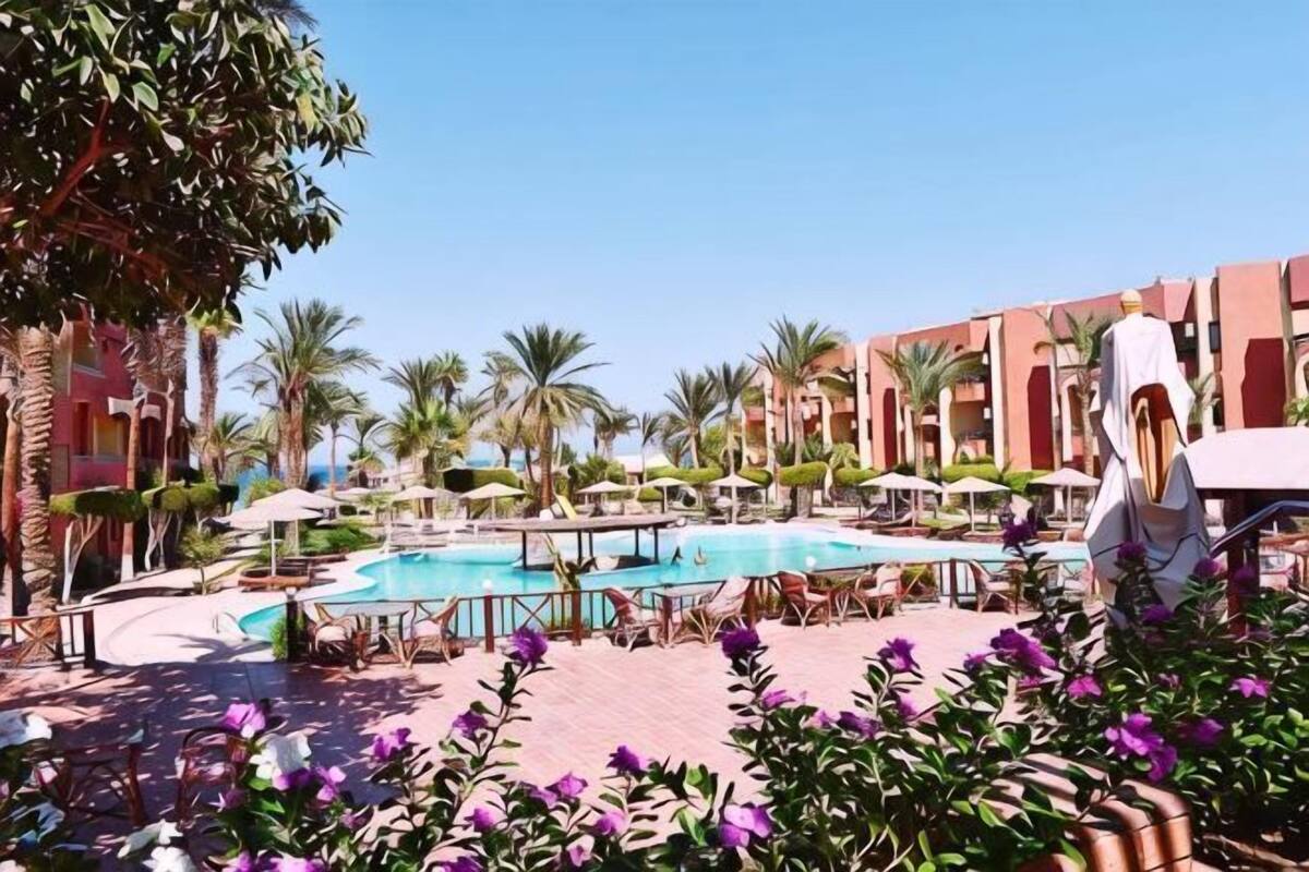 Un espace piscine comprenant plusieurs piscines, des palmiers et un bâtiment doté de balcons.