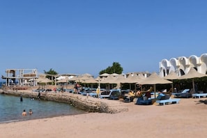 En strand med parasoller, solstolar och ett livräddartorn.