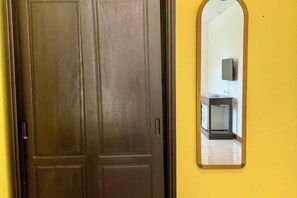 A closed wooden door with a handle, a mirror on the wall reflecting a room with a television and a small table. - KK Hotel Pakse (Pakse)