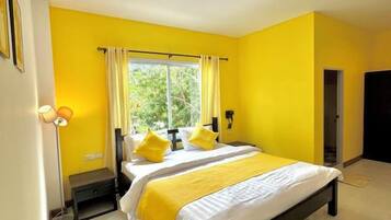 Una habitación con una cama, una mesita de noche, una lámpara y una ventana con cortinas.