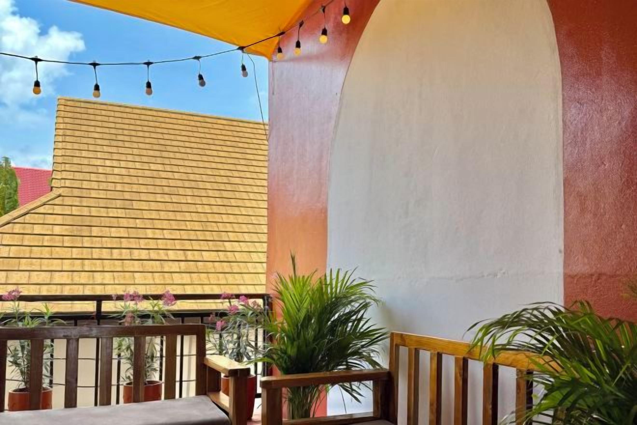 Ein Balkon mit Holzgeländer, Topfpflanzen und Lichterketten.