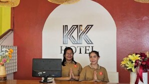 A hotel reception desk with a computer monitor, two staff members, and a large logo on the wall. - KK Hotel Pakse (Pakse)