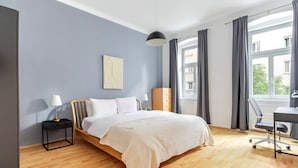 A bedroom with a bed, bedside tables, a desk, and a chair.