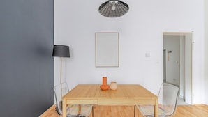 A dining area with a wooden table, two chairs, a lamp, and a framed picture on the wall.