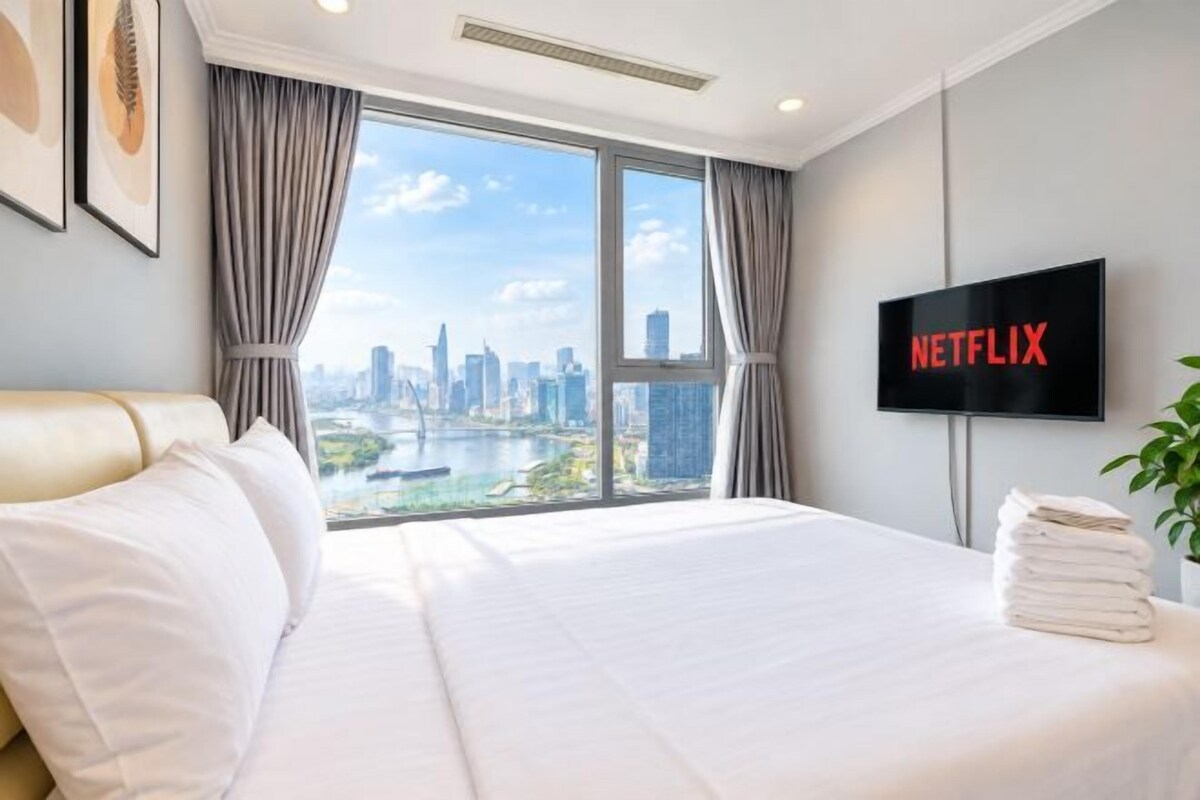A hotel room with a large bed, a television, and a view of a cityscape.