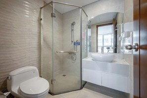 A modern bathroom with a glass-enclosed shower, a white toilet, and a sink with a mirror above it. - Vinhomes Chic Apartment - Ho Chi Minh (Ho Chi Minh City)
