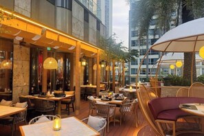 An outdoor dining area with tables and chairs, surrounded by buildings. - Vinhomes Chic Apartment - Ho Chi Minh (Ho Chi Minh City)