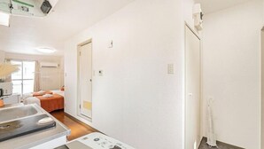 Una habitación de hotel con cama, kitchenette pequeña, baño y zona de ducha.