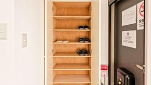 Habitación de hotel con un zapatero de madera, una puerta con letrero de prohibido fumar y un letrero de detector de incendios.