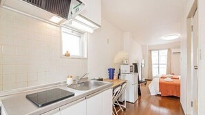 Cocina compacta con fregadero, microondas y un pequeño comedor con sillas.