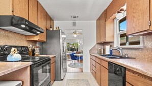 Una cocina moderna con armarios de madera, electrodomésticos de acero inoxidable y vistas al comedor.
