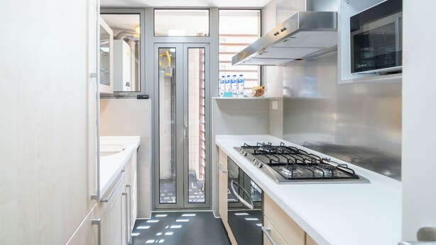 Une cuisine moderne équipée d’une cuisinière à gaz, d’appareils électroménagers en acier inoxydable et offrant une vue à travers une porte vitrée.