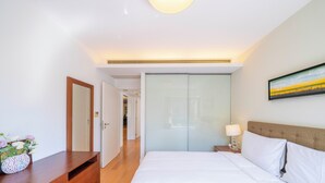 Une chambre d’hôtel avec un lit, une commode en bois, une table de chevet avec une lampe et un tableau au mur.