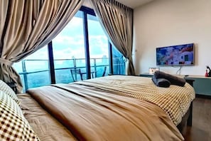 A hotel room with a large bed, curtains, a TV, and a balcony with a view. - C1310 Almas Family Studio Netflix Johor by STAY (Iskandar Puteri)