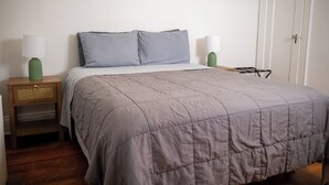 Un dormitorio con cama, dos mesitas de noche y un armario.