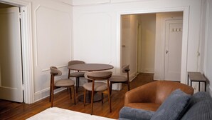 Una habitación con una mesa de comedor redonda y seis sillas, un sofá de cuero marrón y una alfombra blanca.